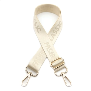 Detail of adjustable beige nylon shoulder strap with golden buckles and woven lettering