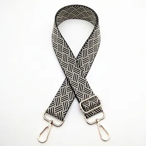 Detail of adjustable black and white woven bag strap with light gold metal lobster clasps