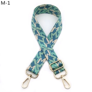 Close-up of adjustable woven bag strap with geometric patterns and gold lobster clasps