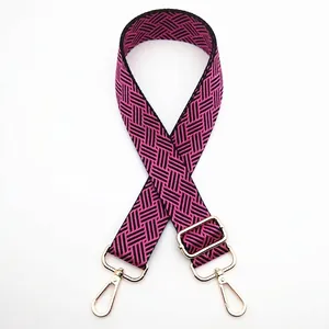 Detailed view of woven pink and black geometric pattern strap with gold metal buckles