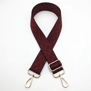 Detail of adjustable woven shoulder strap in burgundy and black with gold metal hardware