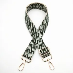 Close-up of woven bag strap in dark green and beige with gold metal lobster clasps