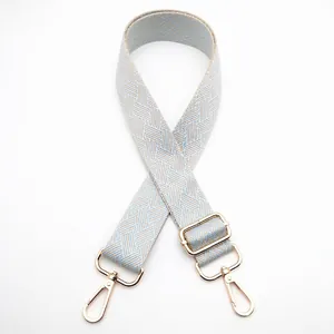Detail of adjustable woven wide bag strap with geometric patterns and gold lobster clasps