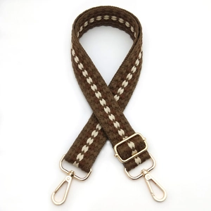 Detail of adjustable woven bag strap with brown stripe pattern and golden metal hooks