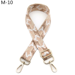 Close-up of beige woven bag strap with geometric pattern and gold metal hooks