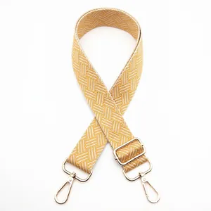 Detail of yellow woven bag strap with geometric patterns and gold metal lobster clasps