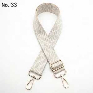 Close-up of beige woven geometric pattern strap with polished gold lobster clasps