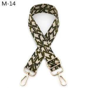 Detail of adjustable woven bag strap with green star patterns and gold metal swivel hooks