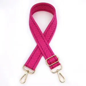 Close-up of adjustable pink shoulder strap with herringbone pattern and gold lobster clasps