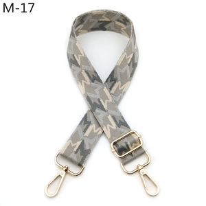 Close-up of adjustable woven strap with grey geometric pattern and gold swivel hooks