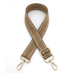 Detail of adjustable woven bag strap with khaki wave pattern and gold metal hardware