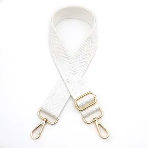 Close-up of white woven bag strap with chevron pattern and polished gold metal hardware