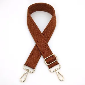 Detail of caramel brown herringbone woven bag strap with golden metal swivel hooks