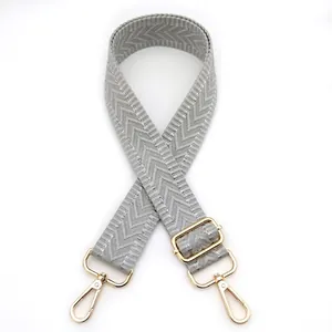 Detail of grey herringbone pattern adjustable strap with gold-tone metal hooks