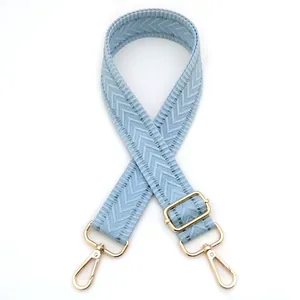 Close-up of light blue braided strap with golden lobster clasps and herringbone texture