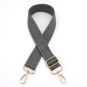 Detail of adjustable gray herringbone woven shoulder strap with gold metal swivel clasps