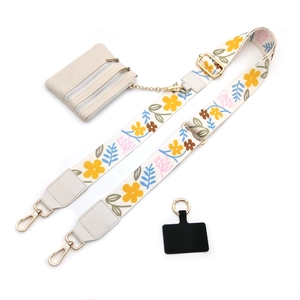 Detail view of floral embroidered wide shoulder strap with a beige triple zipper mini pouch