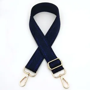 Detail view of navy blue woven fabric bag strap with golden metal swivel lobster clasps