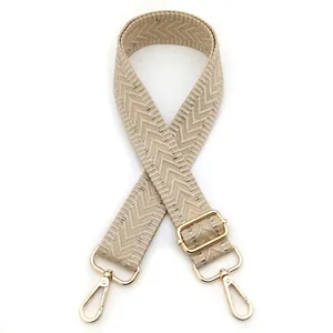 Detail of adjustable beige herringbone strap with high-quality gold metal hardware