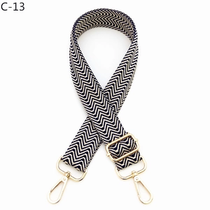Detail of adjustable bag strap with black and white chevron pattern and gold hardware