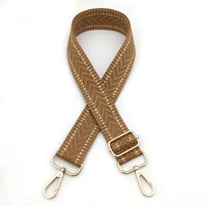 Close-up of brown herringbone woven strap with adjustable gold metal buckles on white background