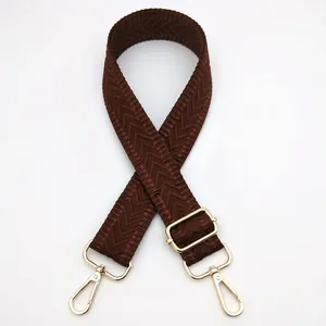 Detail of dark brown herringbone weave bag strap with adjustable light gold metal buckle