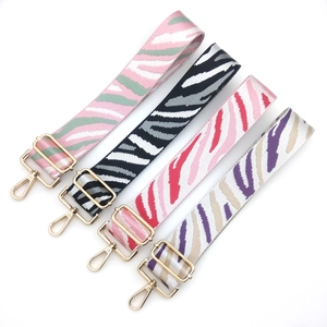Close-up of zebra pattern woven bag straps with gold adjustable buckles and lobster clasps