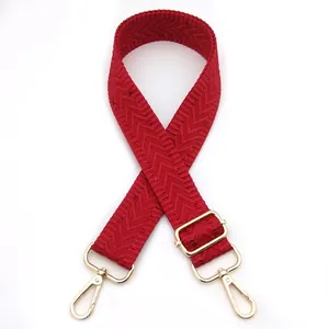 Detailed view of the dark red woven texture and golden lobster clasp on the bag strap
