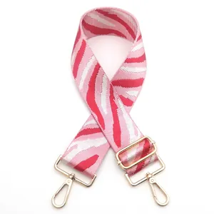 Detail of adjustable woven handbag strap with red zebra pattern and gold metal hooks