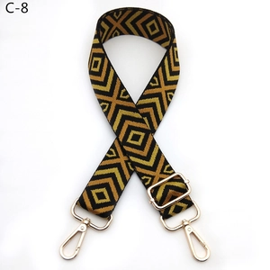 Close-up of adjustable woven bag strap with geometric diamond pattern and gold metal hooks