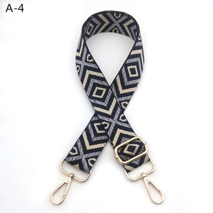 Detailed view of woven canvas bag strap with geometric diamond pattern and gold hardware