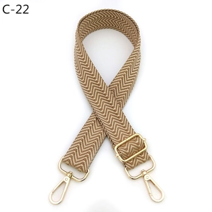 Detail of khaki chevron woven bag strap with golden metal swivel hooks and adjuster buckle