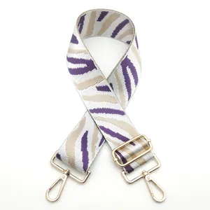 Detail of purple and white zebra stripe shoulder strap with golden metal lobster clasps