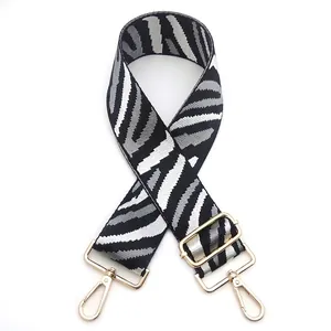 Detail of wide zebra striped replacement bag strap with golden metal lobster clasps