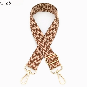 Detail of brown and white chevron patterned bag strap with golden metal lobster clasps