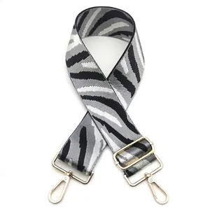 Detailed view of zebra pattern bag strap with gold metal lobster clasps and adjuster