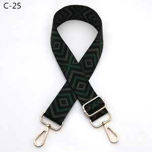 Detail view of adjustable wide purse strap with dark green geometric diamond pattern and gold buckle