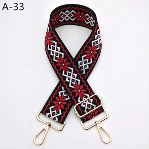 Détail d'une bandoulière en jacquard rouge, noir et blanc avec boucles dorées