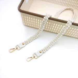 Detail eines gewebten weißen Perlen-Taschenriemens mit goldenen Karabinerverschlüssen