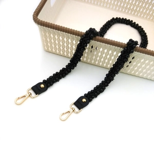 Detail eines handgefertigten schwarzen Perlen-Taschenriemens mit goldenen Karabinern