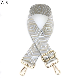 Detail of grey and gold geometric woven bag strap with adjustable metal lobster clasps
