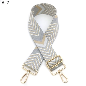 Detail of adjustable wide shoulder strap with grey and gold chevron weave and metal buckles