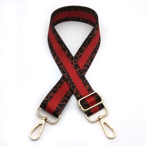 Detail of leopard print bag strap with red stripe and golden metal swivel hooks