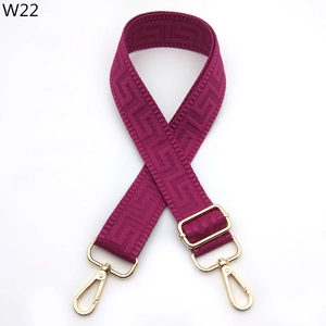 Close-up of adjustable burgundy woven bag strap with golden metal clips and Greek key pattern