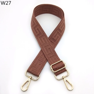 Detail of brown woven bag strap with golden metal snap hooks and Greek key pattern