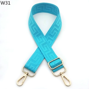 Macro detail of adjustable blue shoulder strap with gold hardware and geometric pattern