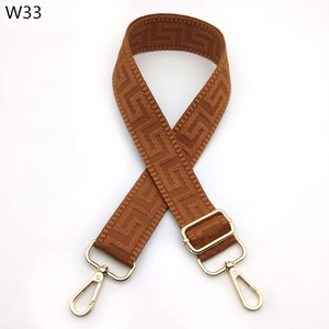 Close-up of adjustable brown geometric jacquard purse strap with gold metal hooks
