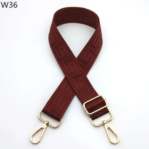 Close-up of adjustable wine red bag strap with Greek key pattern and gold metal buckles