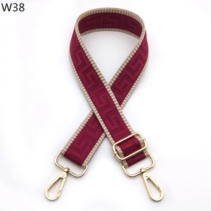 Close-up of wine red adjustable bag strap with beige geometric pattern and gold hooks