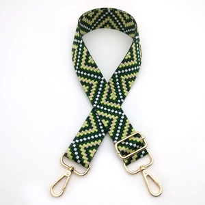 Close-up of green and yellow geometric woven shoulder strap with gold metal hooks